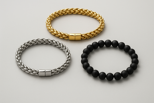Three men’s bracelets arranged on a light gray background: a gold stainless steel rope design at the top, a silver stainless steel rope design on the left, and a matte black beaded stone bracelet on the right.