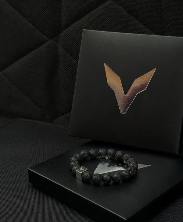 Black bracelet with a logo on a black box with a logo against a dark textured background