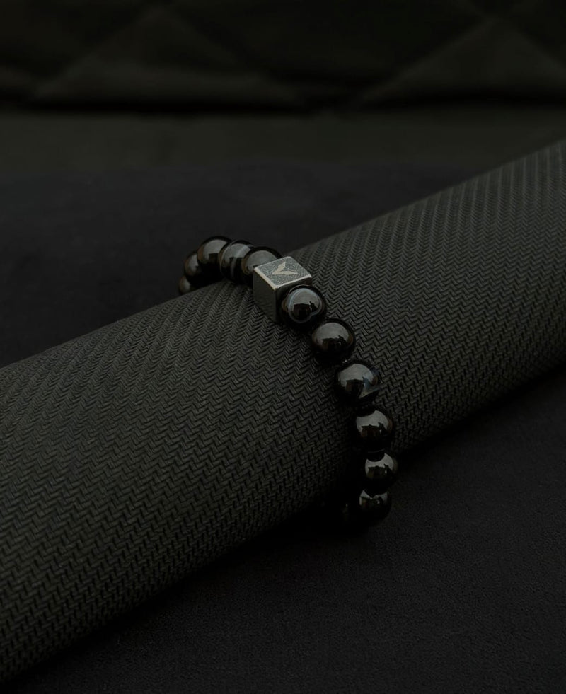 Black beaded bracelet on a black textured surface
