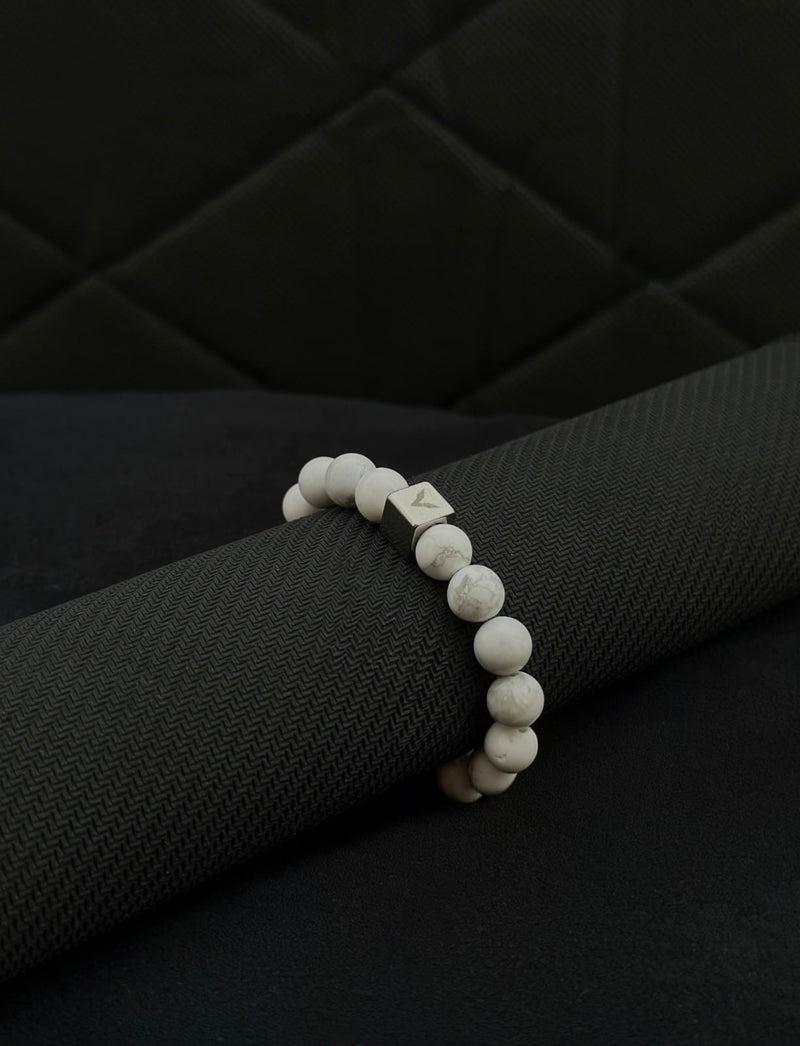White beaded bracelet on a black textured surface