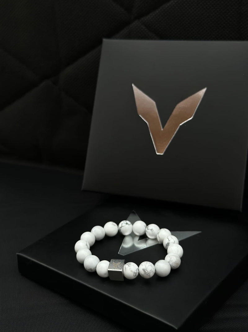 White beaded bracelet on a black box with a logo