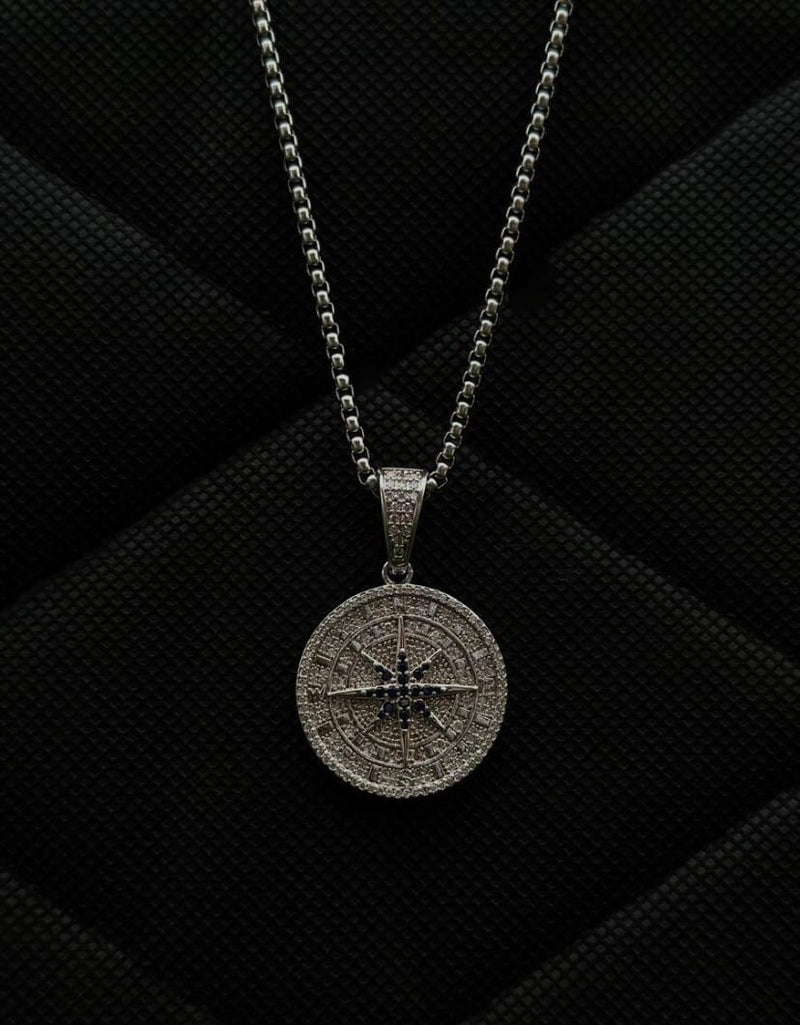 Silver compass pendant necklace on a black textured background
