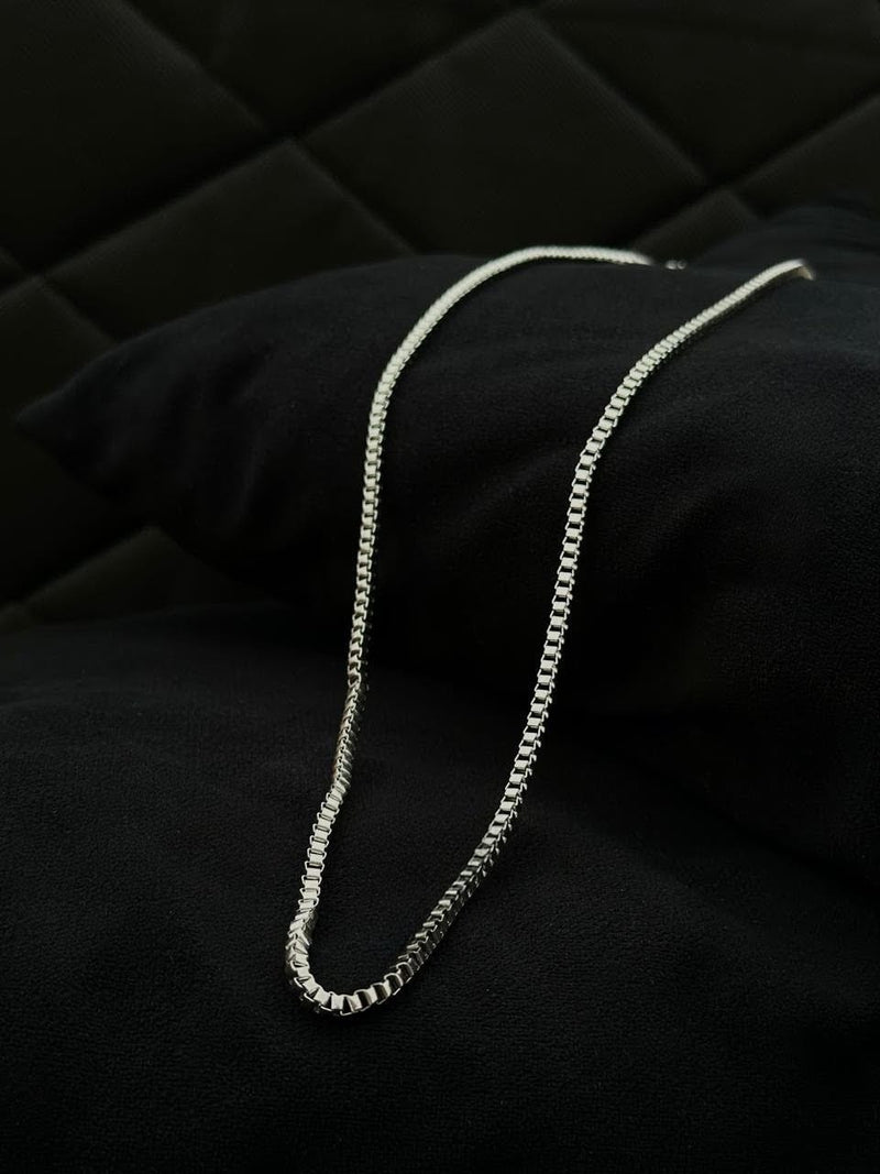 Silver chain necklace on a black textured surface