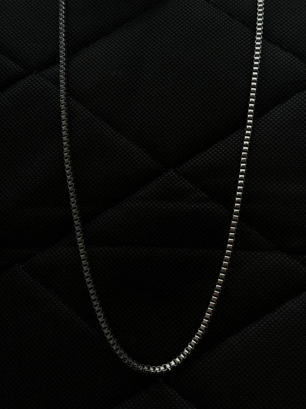 Silver chain necklace on a textured black surface