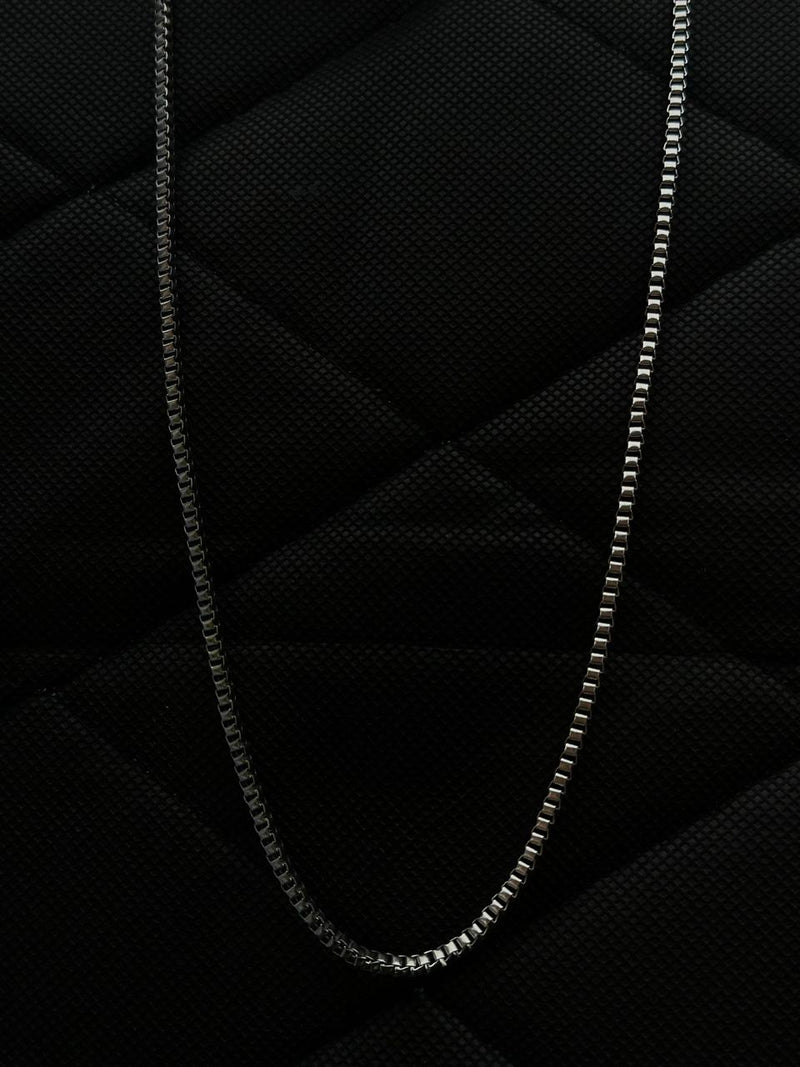 Silver chain necklace on a textured black surface