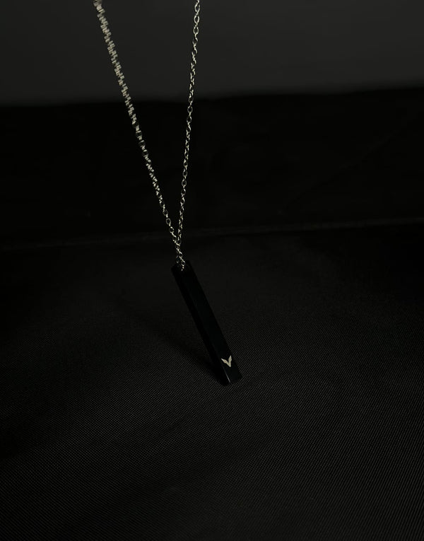 Black pendant necklace on a dark background
