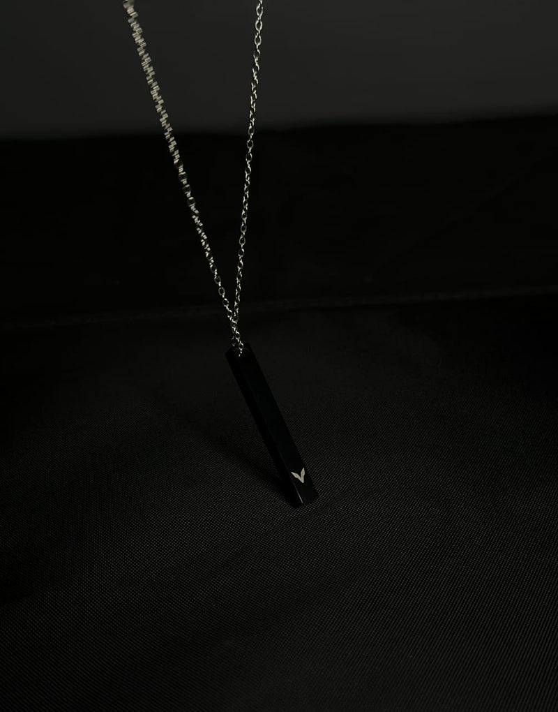 Black pendant necklace on a dark background