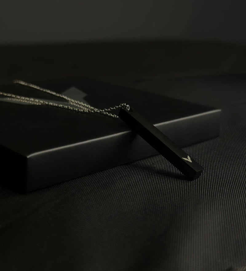 Black pendant on a dark surface with a black box in the background